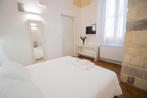 a white bedroom with a bed and a mirror at Sui Tetti Luxury Rooms in Lecce
