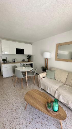 un salon avec un canapé et une table dans l'établissement LE BOHÈME - balcon vue jardin - clim - place de parking - wifi - 5min plage, à La Grande Motte