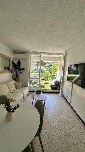 un salon avec un canapé et une table dans l'établissement LE BOHÈME - balcon vue jardin - clim - place de parking - wifi - 5min plage, à La Grande Motte