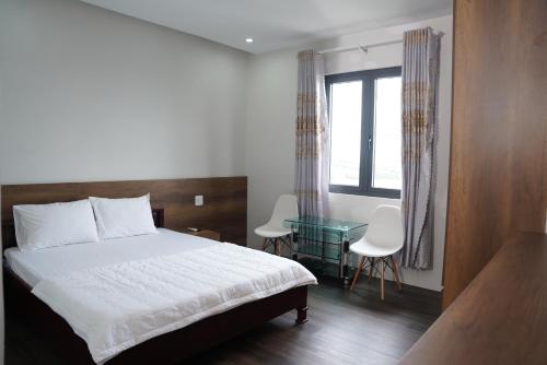 a bedroom with a bed and a table and a window at KHÁCH SẠN ĐẾ VƯƠNG in Cao Lãnh