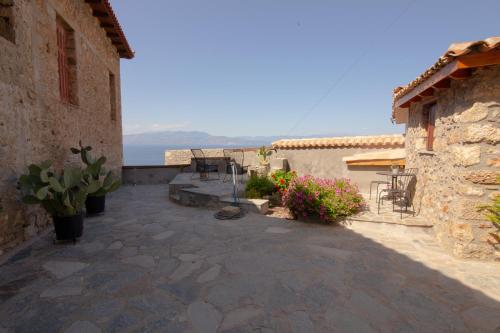 a patio with chairs and flowers next to a building at Fteri Stone House in Platanos, Akrata in Plátanos