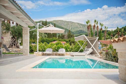 a swimming pool with chairs and an umbrella next to a house at Parga Villas in Parga