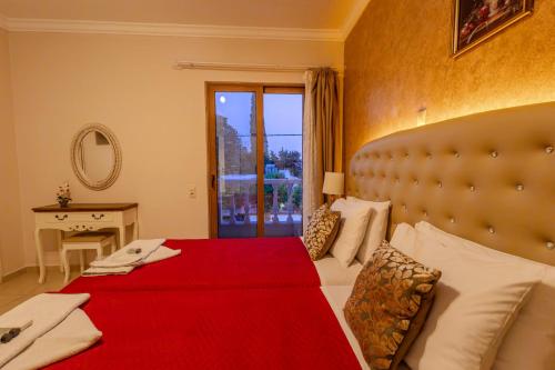 a bedroom with a large bed with a red blanket at Knights' Castle Studios in Archangelos