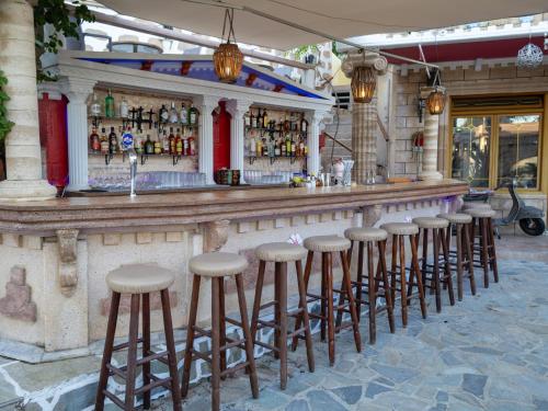 a bar with stools in front of a building at Knights' Castle Studios in Archangelos