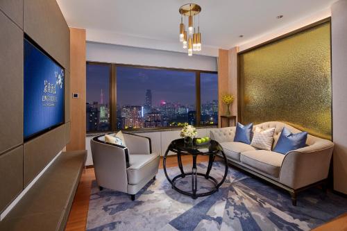 a living room with a couch and two chairs and a television at The Garden Hotel Guangzhou - Discover 26 cultural treasures with hotel Golden Tour Guide in Guangzhou