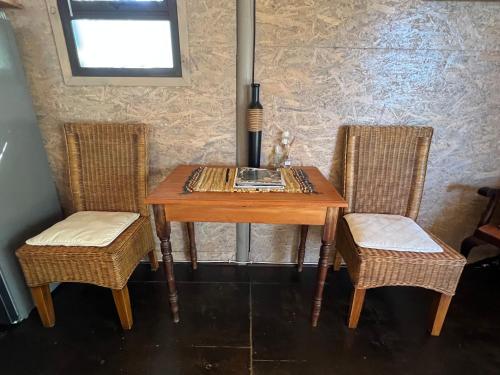 a wooden table with two chairs and a table with a book at Tenikwa Wildlife Centre & Spa in Plettenberg Bay