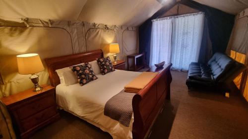 a bedroom with a large bed and a chair at Harties Is Africa Safari Lodge in Hartbeespoort