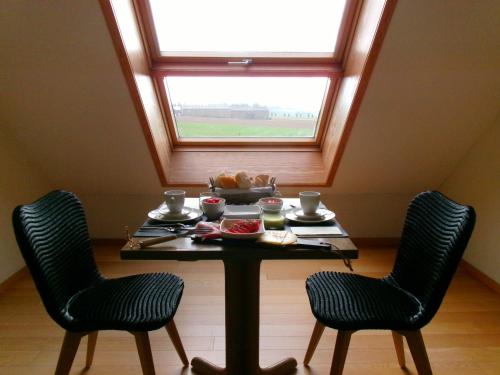 einen Tisch mit 2 Stühlen und ein Fenster in der Unterkunft b&b Kraaiberg in Heuvelland