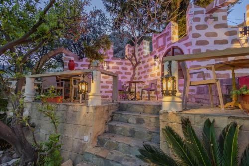 a pink building with stairs and lights on it at Knights' Castle Studios in Archangelos