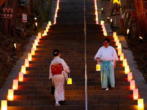 two women walking up a set of stairs with lights at 多武峰観光ホテル in Sakurai