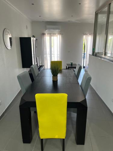 a dining room with a black table and yellow chair at AL Manas Pereira in Castro Marim