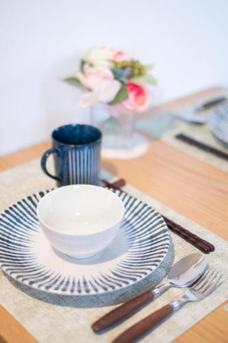 a table with a plate and a bowl and a cup at The Peak Tsutenkaku Elite in Osaka