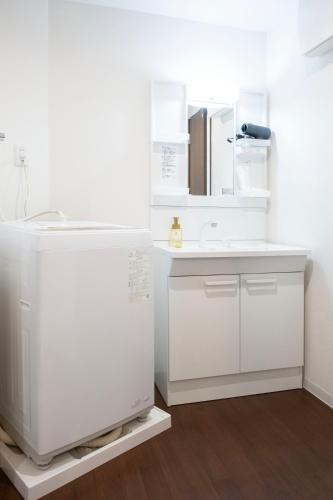 a white bathroom with a sink and a mirror at The Peak Tsutenkaku Elite in Osaka