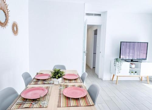 a dining room with a table with pink plates on it at NUEVO, a 70 metros de la playa y con vistas al mar in Cullera