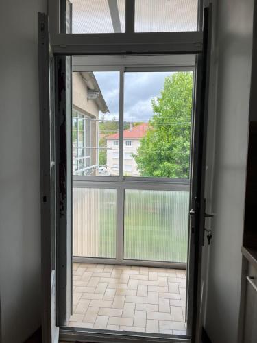 an open glass door with a view of a yard at Hébergement Langogne in Langogne