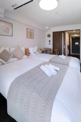 a large white bed with two folded towels on it at The Peak Tsutenkaku Elite in Osaka
