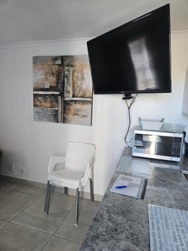 Una sala de estar con un televisor, una silla y un microondas. en Duifie, en Ciudad del Cabo