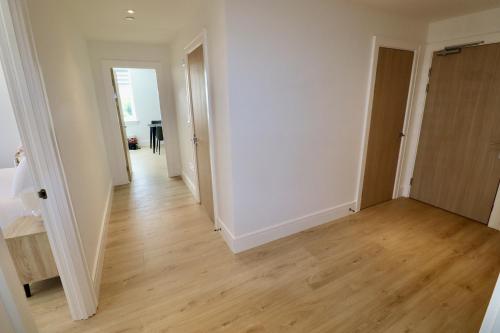 an empty room with white walls and wooden floors at Chertsey Modern 2-Bed Flat with Ensuite, Parking & Ultra-Fast WiFi in Chertsey