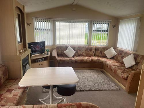 a living room with a couch and a table at Browns caravan rentals, 8 berth, the chase, ingoldmells in Skegness