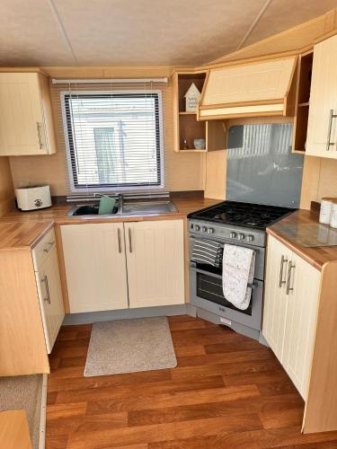 a small kitchen with a stove and a sink at Browns caravan rentals, 8 berth, the chase, ingoldmells in Skegness