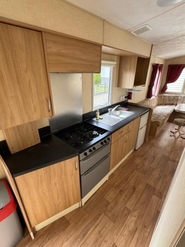 a kitchen with a stove and a sink in a caravan at Alex Domki Angielskie Taras Widokowy in Rewal