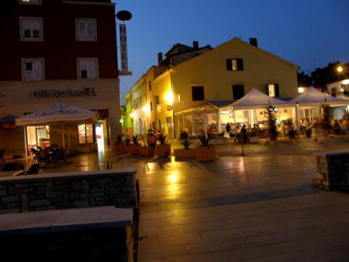 a town square at night with tables and umbrellas at Apartments Tomato in Novigrad Istria