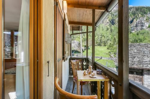 a balcony with a table and a view of a mountain at Casa Andy 2 Val Lavizzara - Happy Rentals in Al Piano