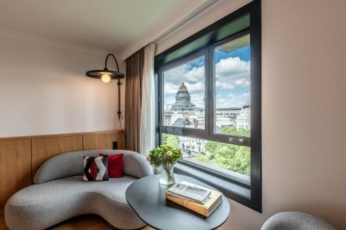 a living room with a chair and a window at Le Louise Hotel Brussels - MGallery Collection in Brussels
