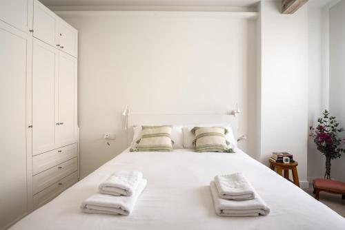a white bedroom with a large white bed with towels on it at Apartamento Vargas 2BDR in Santander