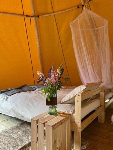 Un dormitorio con una cama y un jarrón de flores sobre una mesa. en Förland Sunnemo, en Sunnemo