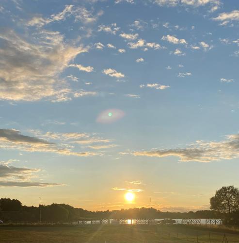 a sunset over a field with the sun in the sky at Domek z widokiem na jezioro in Szkotowo