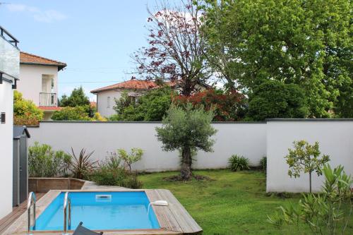 une cour avec une piscine et une clôture blanche dans l'établissement Maison proche plages, au calme, piscine et parking, à Anglet