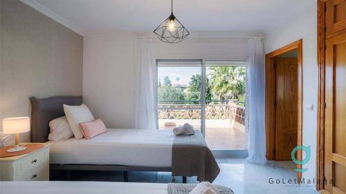a bedroom with a bed and a large window at Villa Hole in One - GoLetMalaga in Mijas Costa