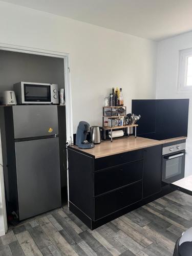 une cuisine avec des armoires noires et un four micro-ondes dans l'établissement Gîte du Haut Pilat, à Saint-Genest-Malifaux