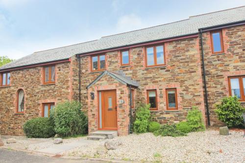 a brick house with a brown door in front of it at Peaceful, rural cottage on the outskirts of Padstow in Padstow