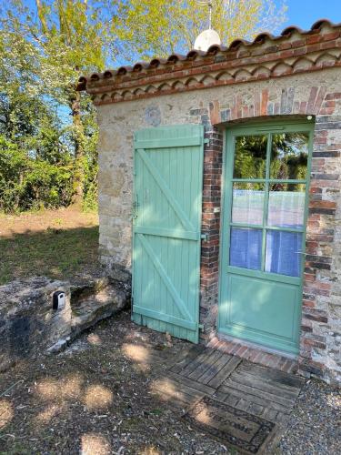 une porte verte sur le côté d'une maison en briques dans l'établissement Gîte Le Petit Ermitage Ste Cécile Vendée, à Collonges-au-Mont-dʼOr