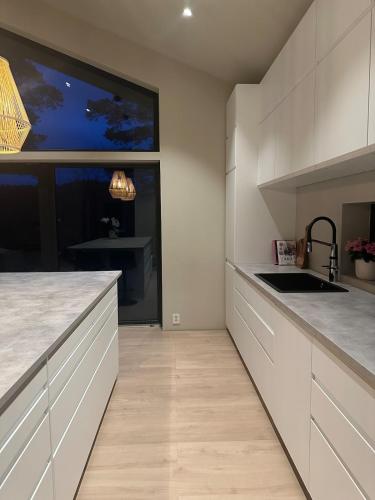 a kitchen with white cabinets and a large window at Melø Panorama design home with magical views in Larvik