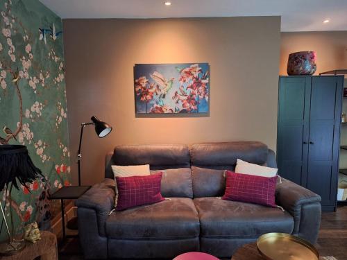 a living room with a brown couch and a painting at Boshuisje Het Bosnest - de Specht bungalow met privétuin op Hoefbos Otterlo Veluwe in Otterlo