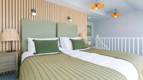 - une chambre dotée d'un grand lit avec des draps blancs et des oreillers verts dans l'établissement 3 Beach Terrace, à Rhosneigr