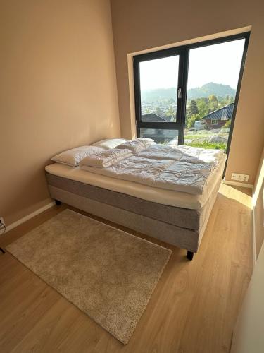 a bed in a room with a large window at Melø Panorama design home with magical views in Larvik