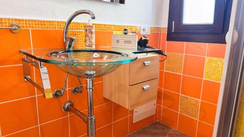een badkamer met een glazen wastafel en oranje tegels bij La casa delle Stelle by Ca-Sa Check in San Teodoro
