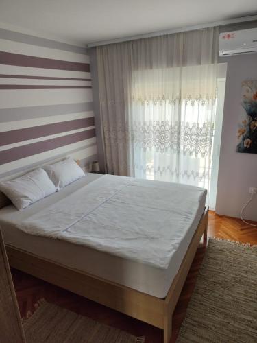 a large bed in a bedroom with a window at Apartment Nibim in Bijela