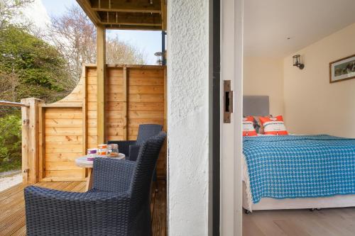 a bedroom with a bed and a balcony with blue chairs at Mill End Hotel in Chagford