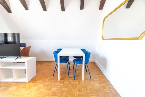 - une table blanche avec des chaises bleues dans la chambre dans l'établissement Le Donjon de Plumereau, à Tours