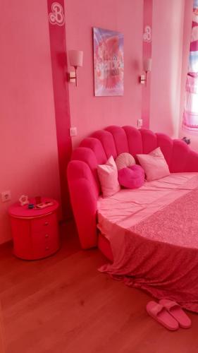 a pink bedroom with a large bed with a pink couch at Тематичен Пентхаус Несебър България in Nesebar