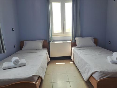 two beds in a room with a window at Aegean Balconies in Vromolithos Beach, Leros in Vromolithos