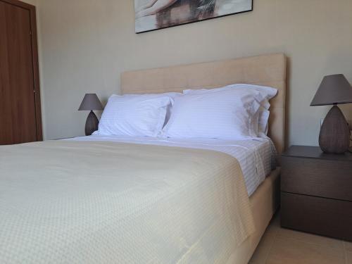 a bedroom with a bed with white sheets and pillows at Aegean Balconies in Vromolithos Beach, Leros in Vromolithos