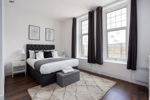 a bedroom with a large bed and two windows at 1 Bed Apartments, 2 Mins to Beach, Sleeps 4 in Southend-on-Sea