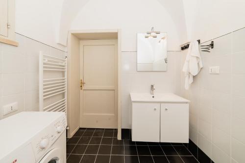 a white bathroom with a sink and a washing machine at CASA PAPADIA in Uggiano la Chiesa