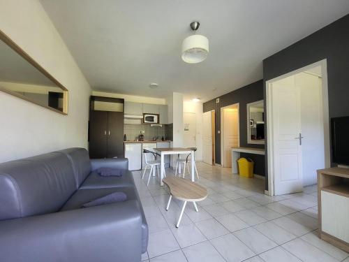 un salon avec un canapé bleu et une cuisine dans l'établissement La terrasse de Babylone, calme et relaxant, au Cap d'Agde